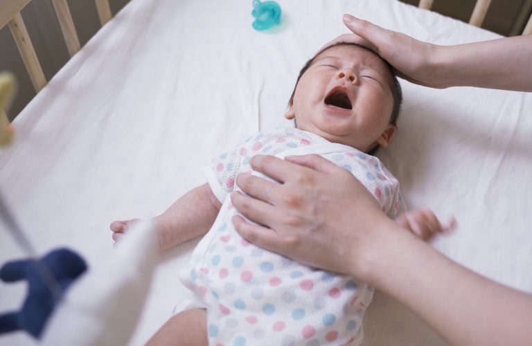 Bé sơ sinh khóc trong nôi do bị lẫn lộn ngày đêm khi ngủ.