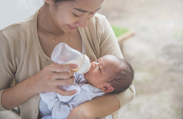 Mẹ bế bé trên khủy tay và cho bé bú bình