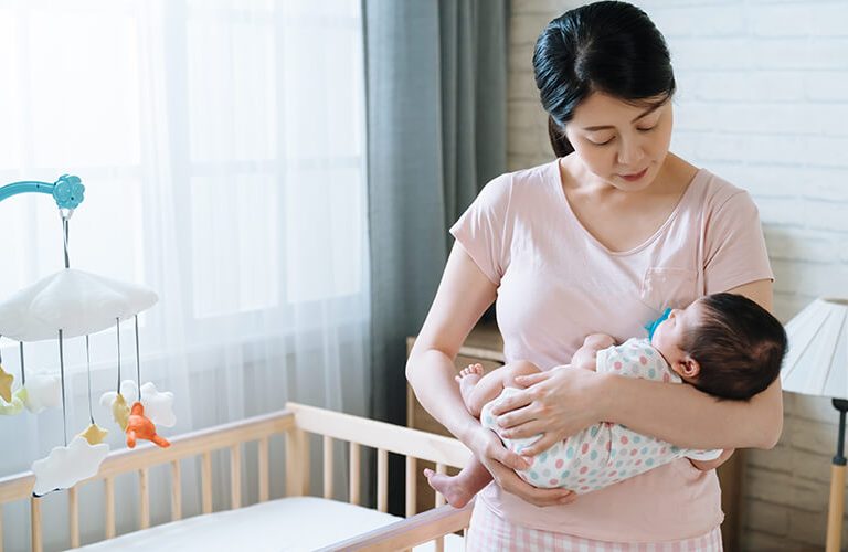 Mẹ bế trẻ sơ sinh lên khi luyện ngủ cho bé theo phương pháp bế lên đặt xuống.