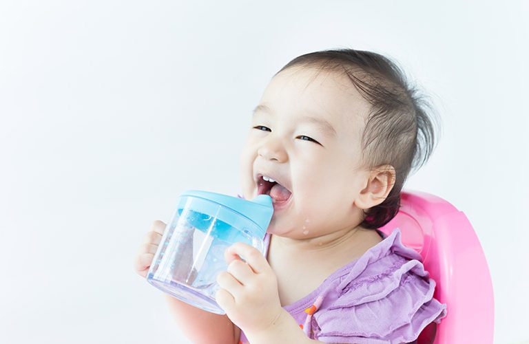 Bé gái tự cầm bình khi uống nước