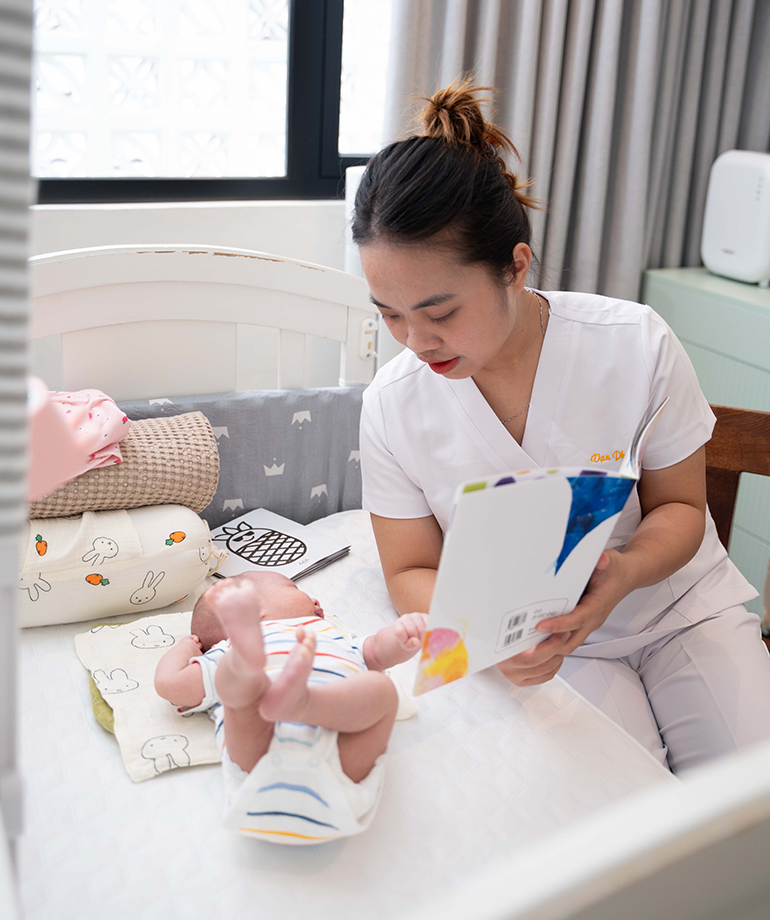 Bảo mẫu Vạn Phúc Care cho bé nhìn tranh ảnh để phát triển các kỹ năng