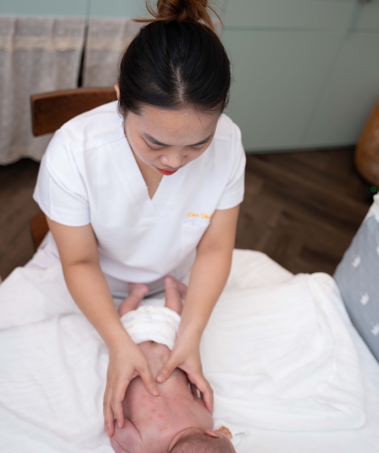 Điều dưỡng viên Vạn Phúc Care massage cho bé trước khi tắm.