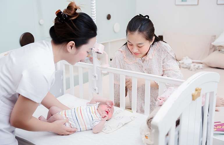 Mẹ quan sát bảo mẫu chăm sóc bé.