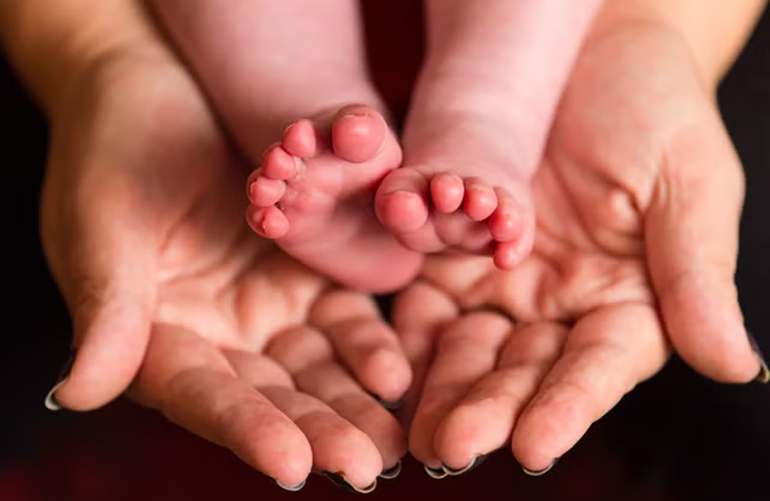 Bàn chân trẻ sơ sinh và bàn tay mẹ